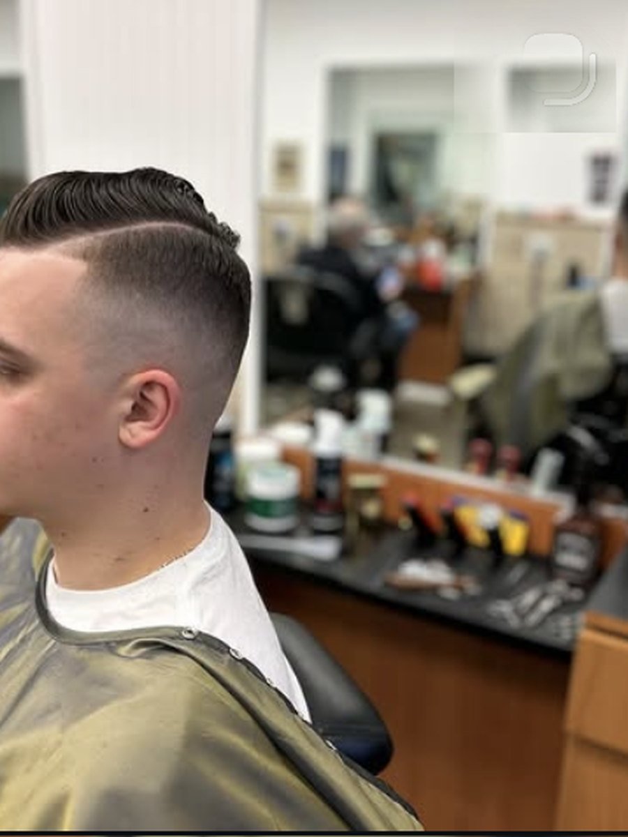 Skin fade with a hard part cut into the side at Plaza Barber Shop West Hempstead